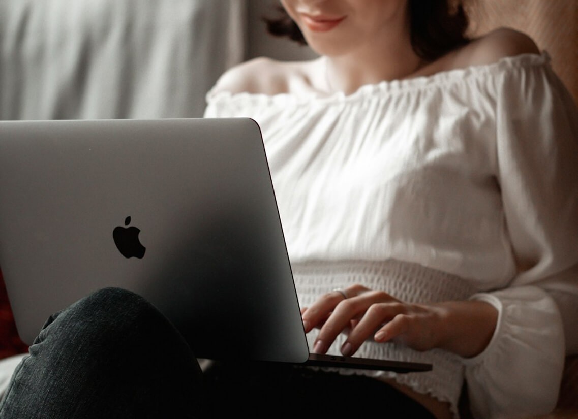 Person in a white off-shoulder top using a MacBook laptop, with text overlay 'What's new in digital?' and the शून्य कथा logo in the top corner.